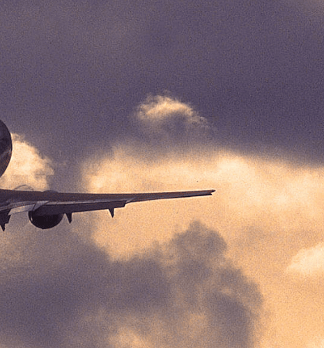 Image of an airplane in the sky under sunlit clouds