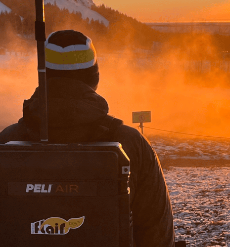 Scientifique portant la Flair box sur son dos dans un environnement naturel au lever du soleil